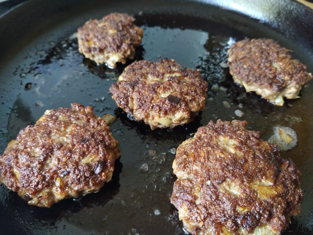 burger meat in grease on a pan